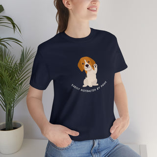 Easily Distracted Unisex Jersey Short Sleeve Tee in Navy. Shown is front design featuring a dog waving with the saying "Easily Distracted by Dogs" below it. The back of shirt has the classic Benefit Beagle Logo.