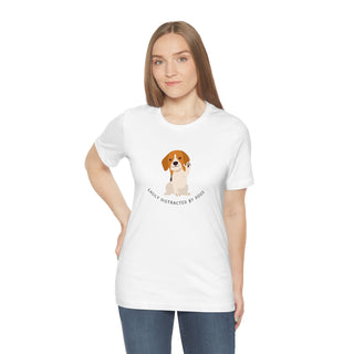 Easily Distracted Unisex Jersey Short Sleeve Tee in White. Shown is front design featuring a dog waving with the saying "Easily Distracted by Dogs" below it. The back of shirt has the classic Benefit Beagle Logo.