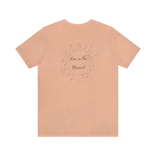 Live in the Moment Unisex Short Sleeve Tee in Heather Peach. The Live in the Moment design features a graphic on the back with the phrase "Live in the Moment" surrounded by shooting stars.