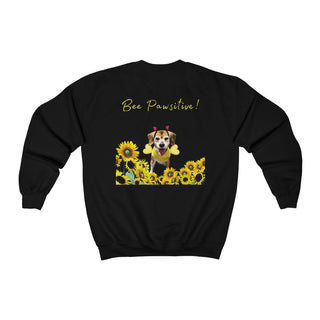 Bee Pawsitive Unisex Crewneck Sweatshirt shirt in Black. Shown is back of shirt showcasing a dog dressed as as bee in a a field of sunflowers with the phrase "Bee Pawsitive!" above it. The front features the Bee Pawsitive Benefit Beagle Logo.