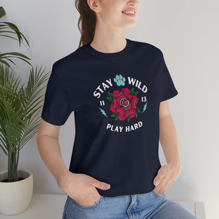 Stay Wild Unisex Premium Tee in Navy. Shown is front of Stay Wild Design features a tattoo style rose with the phrase "Stay Wild, Play Hard" around it. The back of shirt features the Stay Wild Benefit Beagle Logo Design.