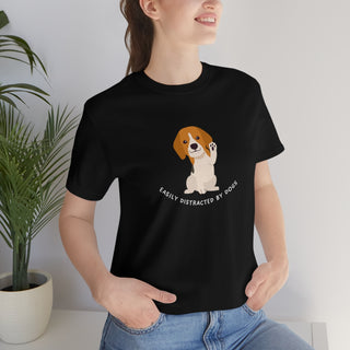 Easily Distracted Unisex Jersey Short Sleeve Tee in Black. Shown is front design featuring a dog waving with the saying "Easily Distracted by Dogs" below it. The back of shirt has the classic Benefit Beagle Logo.