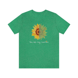 You are my Sunshine Unisex Jersey Short Sleeve Tee in Heather Kelly. Shown is the front showcasing a sunflower which is split down the middle and half is made out of paw prints. Underneath is the phrase "You are my Sunshine" . Back of shirt features the Sunflower Benefit Beagle Logo.