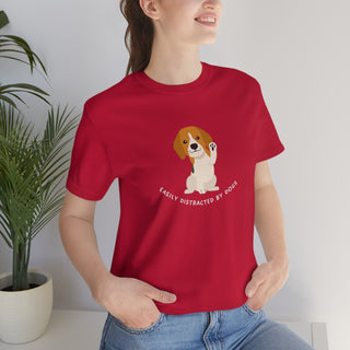 Easily Distracted Unisex Jersey Short Sleeve Tee in Red. Shown is front design featuring a dog waving with the saying "Easily Distracted by Dogs" below it. The back of shirt has the classic Benefit Beagle Logo.