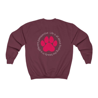 Different Pawspective Unisex Crewneck Sweatshirt in Maroon. Shown is the back of shirt featuring a large colorful pawprint with the the phrase "Life is all about finding the beauty in a different pawspective" circled around it. The Benefit Beagle Logo is located in the top corner on the front of shirt.