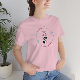 Dog Hair is my Glitter Unisex Jersey Short Sleeve Tee in pink. The Dog Hair is my Glitter design features a dog with the phrase "Dog Hair is my Glitter" above it and it is surrounded by a circle with paw prints.