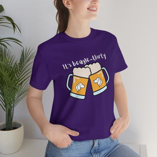 Beagle-Thirty Mugs Unisex Jersey Short Sleeve Tee in Team Purple. The front of shirt showcases Two Dog Adorned Mugs clinking with the saying, "It's Beagle-Thirty" above it. Back of shirt features corresponding Benefit Beagle Logo.