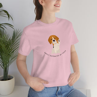 Easily Distracted Unisex Jersey Short Sleeve Tee in Pink. Shown is front design featuring a dog waving with the saying "Easily Distracted by Dogs" below it. The back of shirt has the classic Benefit Beagle Logo.