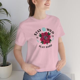 Stay Wild Unisex Premium Tee in Pink. Shown is front of Stay Wild Design features a tattoo style rose with the phrase "Stay Wild, Play Hard" around it. The back of shirt features the Stay Wild Benefit Beagle Logo Design.