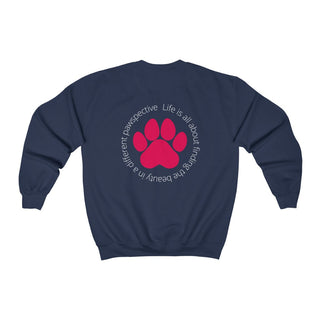 Different Pawspective Unisex Crewneck Sweatshirt in Navy. Shown is the back of shirt featuring a large colorful pawprint with the the phrase "Life is all about finding the beauty in a different pawspective" circled around it. The Benefit Beagle Logo is located in the top corner on the front of shirt.