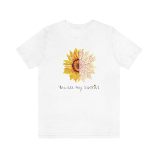 You are my Sunshine Unisex Jersey Short Sleeve Tee in White. Shown is the front showcasing a sunflower which is split down the middle and half is made out of paw prints. Underneath is the phrase "You are my Sunshine" . Back of shirt features the Sunflower Benefit Beagle Logo.