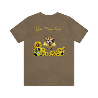 Bee Pawsitive Unisex Jersey Short Sleeve Tee shirt in Heather Olive. Shown is back of shirt showcasing a dog dressed as as bee in a a field of sunflowers with the phrase "Bee Pawsitive!" above it. The front features the Bee Pawsitive Benefit Beagle Logo.