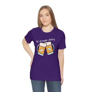 Beagle-Thirty Mugs Unisex Jersey Short Sleeve Tee in Team Purple. The front of shirt showcases Two Dog Adorned Mugs clinking with the saying, "It's Beagle-Thirty" above it. Back of shirt features corresponding Benefit Beagle Logo.