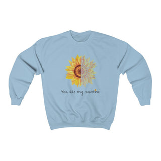 You are my Sunshine Unisex Crewneck Sweatshirt in Light Blue. Shown is the front showcasing a sunflower which is split down the middle and half is made out of paw prints. Underneath is the phrase "You are my Sunshine" . Back of shirt features the Sunflower Benefit Beagle Logo.