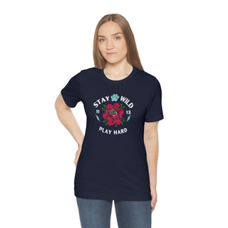 Stay Wild Unisex Premium Tee in Navy. Shown is front of Stay Wild Design features a tattoo style rose with the phrase "Stay Wild, Play Hard" around it. The back of shirt features the Stay Wild Benefit Beagle Logo Design.