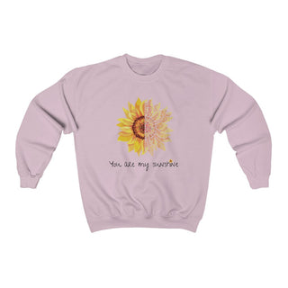 You are my Sunshine Unisex Crewneck Sweatshirt in Light Pink. Shown is the front showcasing a sunflower which is split down the middle and half is made out of paw prints. Underneath is the phrase "You are my Sunshine" . Back of shirt features the Sunflower Benefit Beagle Logo.