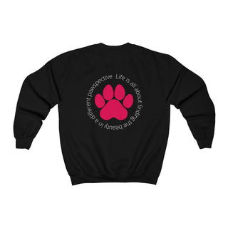 Different Pawspective Unisex Crewneck Sweatshirt in Black. Shown is the back of shirt featuring a large colorful pawprint with the the phrase "Life is all about finding the beauty in a different pawspective" circled around it. The Benefit Beagle Logo is located in the top corner on the front of shirt.