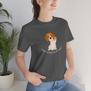 Easily Distracted Unisex Jersey Short Sleeve Tee in Asphalt. Shown is front design featuring a dog waving with the saying "Easily Distracted by Dogs" below it. The back of shirt has the classic Benefit Beagle Logo.