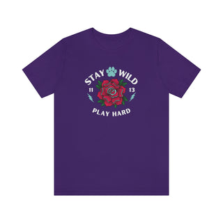 Stay Wild Unisex Premium Tee in Team Purple. Shown is front of Stay Wild Design features a tattoo style rose with the phrase "Stay Wild, Play Hard" around it. The back of shirt features the Stay Wild Benefit Beagle Logo Design.