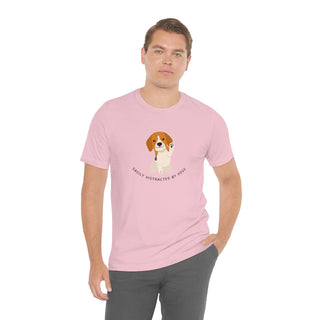 Easily Distracted Unisex Jersey Short Sleeve Tee in Pink. Shown is front design featuring a dog waving with the saying "Easily Distracted by Dogs" below it. The back of shirt has the classic Benefit Beagle Logo.