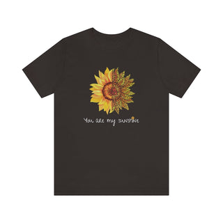 You are my Sunshine Unisex Jersey Short Sleeve Tee in Light Chocolate Brown. Shown is the front showcasing a sunflower which is split down the middle and half is made out of paw prints. Underneath is the phrase "You are my Sunshine" . Back of shirt features the Sunflower Benefit Beagle Logo.