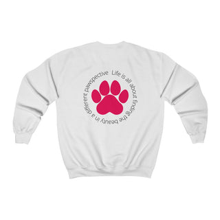 Different Pawspective Unisex Crewneck Sweatshirt in White. Shown is the back of shirt featuring a large colorful pawprint with the the phrase "Life is all about finding the beauty in a different pawspective" circled around it. The Benefit Beagle Logo is located in the top corner on the front of shirt.