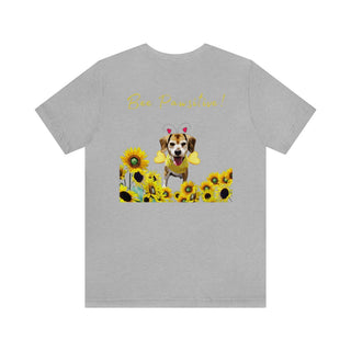 Bee Pawsitive Unisex Jersey Short Sleeve Tee shirt in Athletic Heather. Shown is back of shirt showcasing a dog dressed as as bee in a a field of sunflowers with the phrase "Bee Pawsitive!" above it. The front features the Bee Pawsitive Benefit Beagle Logo.