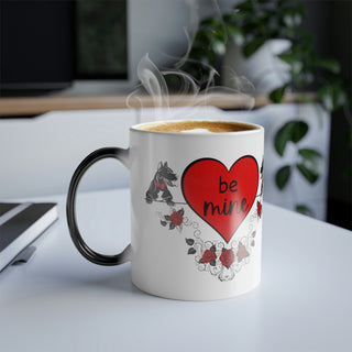 Color morphing mug with dogs with bowties and roses and the center hearts reading, "be mine" and "furever". Mug is white with design when filled with hot beverage. When cool or empty, mug color morphs to dark.