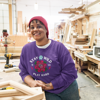 Stay Wild Unisex Heavy Blend Crewneck Sweatshirt in Purple. The Stay Wild Design features a tattoo style rose with the phrase "Stay Wild, Play Hard" around it. The back of shirt features the Stay Wild Benefit Beagle Logo Design.