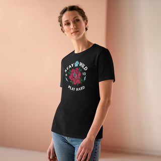 Stay Wild Women's Premium Tee in Black. Shown is front of Stay Wild Design features a tattoo style rose with the phrase "Stay Wild, Play Hard" around it. The back of shirt features the Stay Wild Benefit Beagle Logo Design.