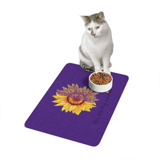 You are my Sunshine Pet Food Mat in Purple. The design features a sunflower which is split down the middle and half is made out of paw prints. There is the phrase "You are my Sunshine" at the bottom of the design.