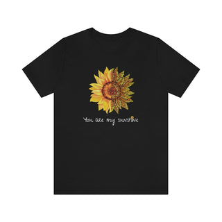 You are my Sunshine Unisex Jersey Short Sleeve Tee in Black. Shown is the front showcasing a sunflower which is split down the middle and half is made out of paw prints. Underneath is the phrase "You are my Sunshine" . Back of shirt features the Sunflower Benefit Beagle Logo.