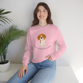 Easily Distracted Unisex Heavy Blend Crewneck Sweatshirt in Pink. Shown is front design featuring a dog waving with the saying "Easily Distracted by Dogs" below it. The back of shirt has the classic Benefit Beagle Logo.