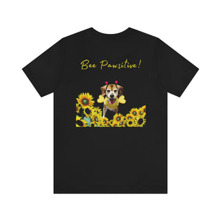 Bee Pawsitive Unisex Jersey Short Sleeve Tee shirt in Black. Shown is back of shirt showcasing a dog dressed as as bee in a a field of sunflowers with the phrase "Bee Pawsitive!" above it. The front features the Bee Pawsitive Benefit Beagle Logo.