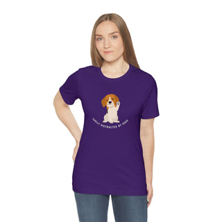 Easily Distracted Unisex Jersey Short Sleeve Tee in Team Purple. Shown is front design featuring a dog waving with the saying "Easily Distracted by Dogs" below it. The back of shirt has the classic Benefit Beagle Logo.