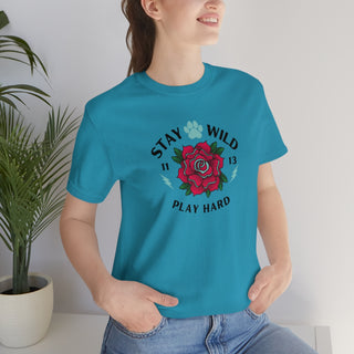 Stay Wild Unisex Premium Tee in Aqua. Shown is front of Stay Wild Design features a tattoo style rose with the phrase "Stay Wild, Play Hard" around it. The back of shirt features the Stay Wild Benefit Beagle Logo Design.