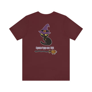 Witchy Cat Unisex Jersey Short Sleeve Tee. Back side shown in Maroon with Wide Eyed Cartoon Cat wearing Purple Hat Standing over Broom. "Crossing Paths Since 1692". On the front of shirt is similar Witchy Benefit Beagle Logo. Purrfect for Halloween, or anytime!