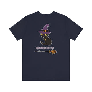 Witchy Cat Unisex Jersey Short Sleeve Tee. Back side shown in Navy with Wide Eyed Cartoon Cat wearing Purple Hat Standing over Broom. "Crossing Paths Since 1692". On the front of shirt is similar Witchy Benefit Beagle Logo. Purrfect for Halloween, or anytime!