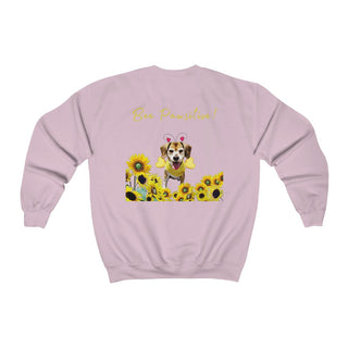 Bee Pawsitive Unisex Crewneck Sweatshirt shirt in Light Pink. Shown is back of shirt showcasing a dog dressed as as bee in a a field of sunflowers with the phrase "Bee Pawsitive!" above it. The front features the Bee Pawsitive Benefit Beagle Logo.