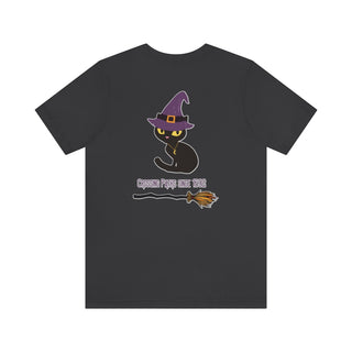 Witchy Cat Unisex Jersey Short Sleeve Tee. Back side shown in Dark Grey with Wide Eyed Cartoon Cat wearing Purple Hat Standing over Broom. "Crossing Paths Since 1692". On the front of shirt is similar Witchy Benefit Beagle Logo. Purrfect for Halloween, or anytime!