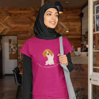 Easily Distracted Women's Midweight Cotton Tee in Team Heliconia Pink. Shown is front design featuring a dog waving with the saying "Easily Distracted by Dogs" below it. The back of shirt has the classic Benefit Beagle Logo.