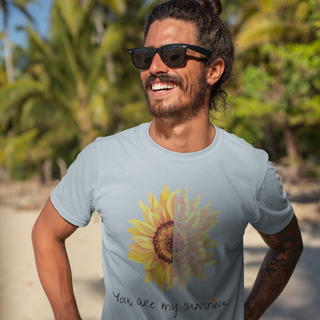 You are my Sunshine Unisex Jersey Short Sleeve Tee in Light Blue. Shown is the front showcasing a sunflower which is split down the middle and half is made out of paw prints. Underneath is the phrase "You are my Sunshine" . Back of shirt features the Sunflower Benefit Beagle Logo.