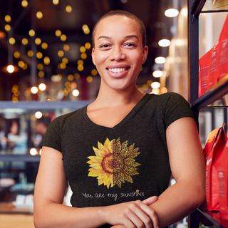 You are my Sunshine Unisex V-Neck Tee in Black. Shown is the front showcasing a sunflower which is split down the middle and half is made out of paw prints. Underneath is the phrase "You are my Sunshine" . Back of shirt features the Sunflower Benefit Beagle Logo.